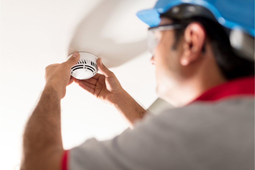 A professional fixing smoke detector in a room.
